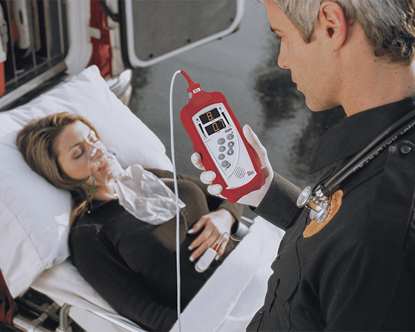 Secouriste surveillant un patient inconscient sur un brancard à côté d’une ambulance.